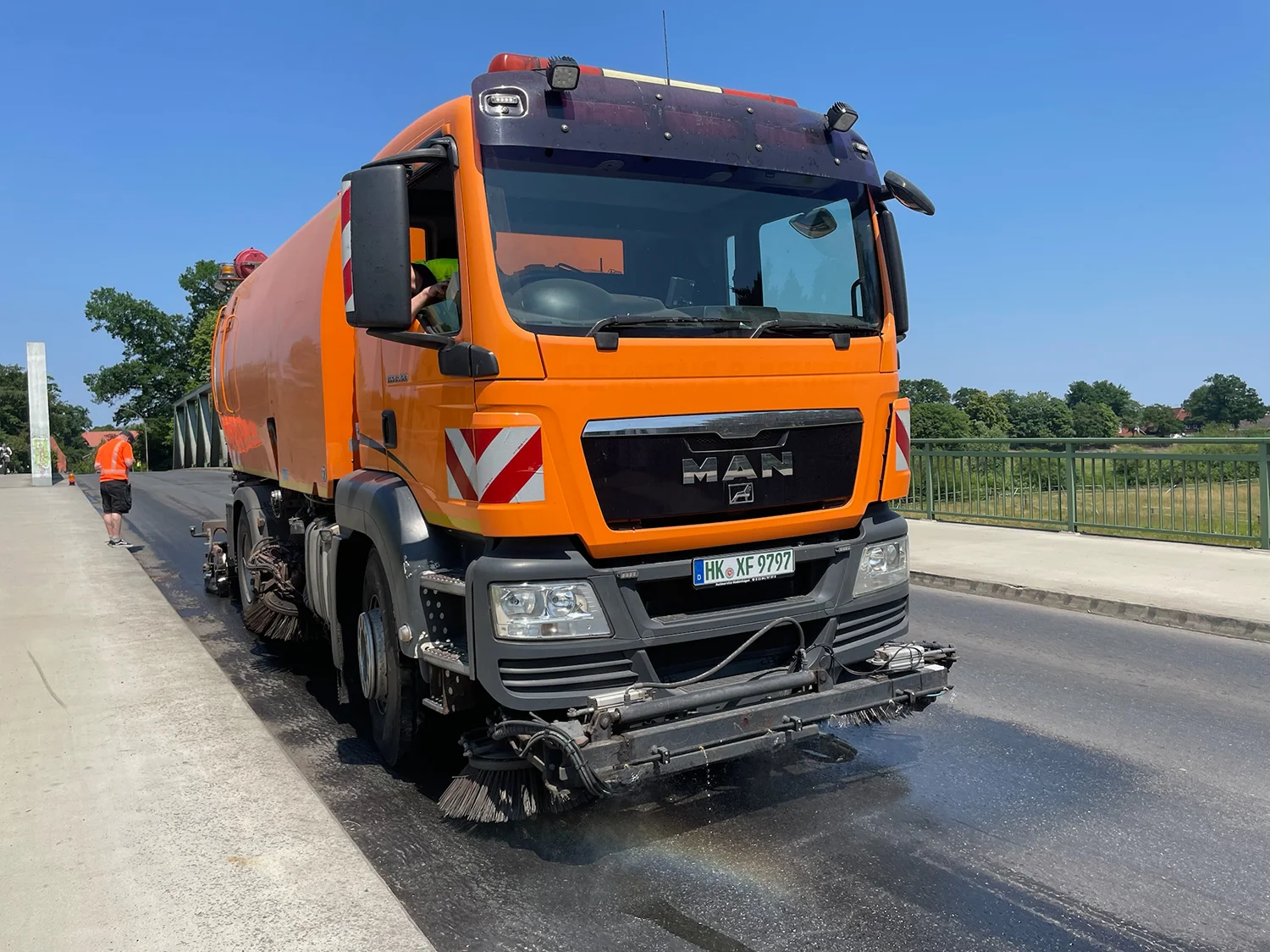 Straßenkehrmaschine reinigt eine Ölspur auf einer Brücke