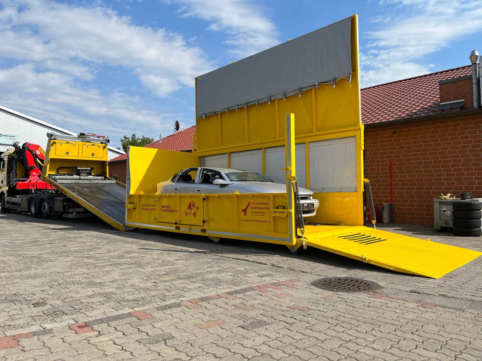 Ein Unfallwagen steht in einem Hochvoltcontainer, der von einem Abschleppwagen abgeladen wurde